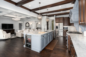 Remodeled kitchen and family room combo with large white island with marble countertops,, dark wood floors, and cabinets